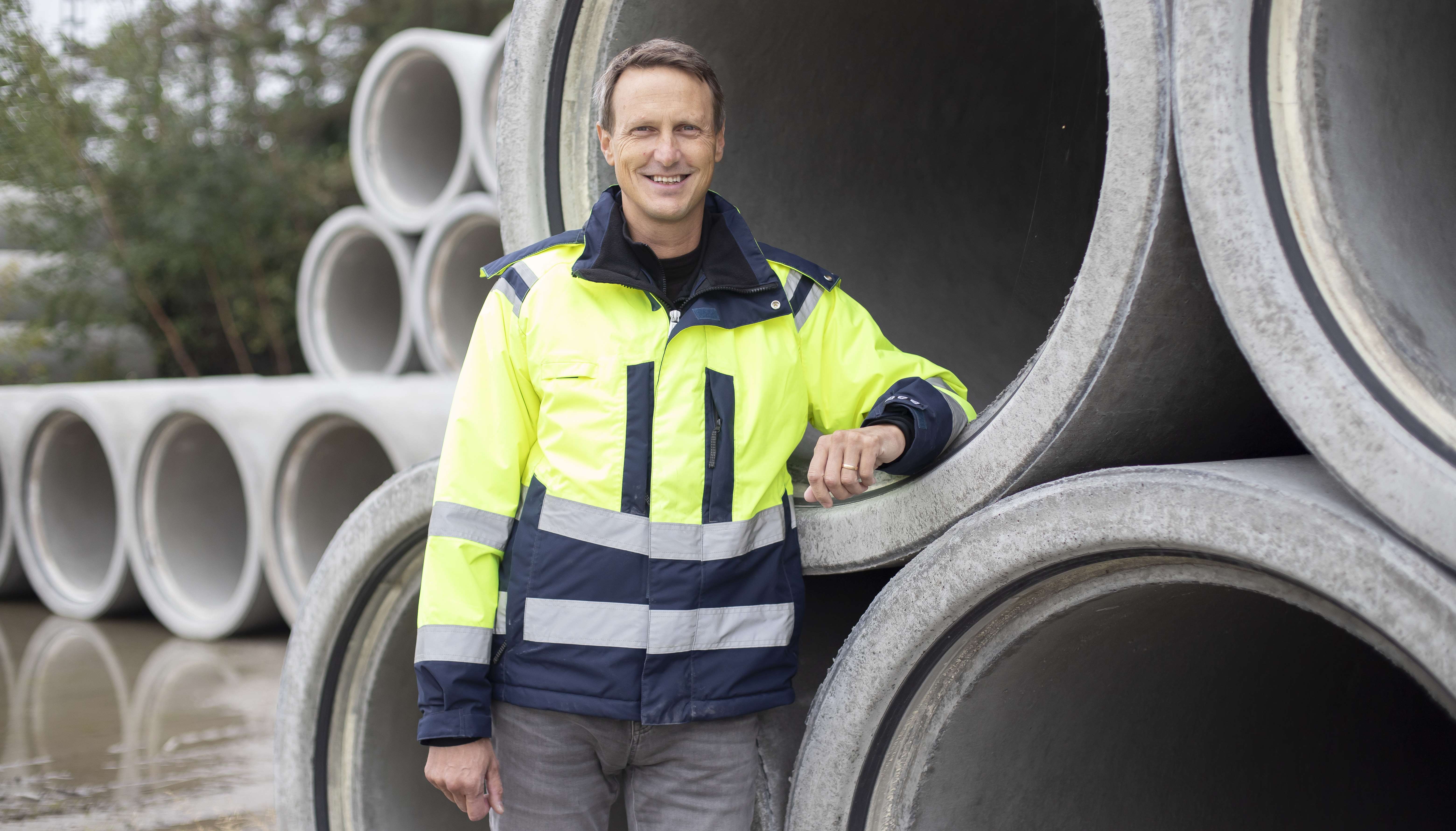 En glad man står framför ett gäng rör. 