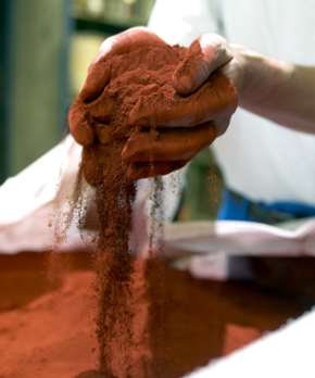 Händer håller i rött färgpigment.