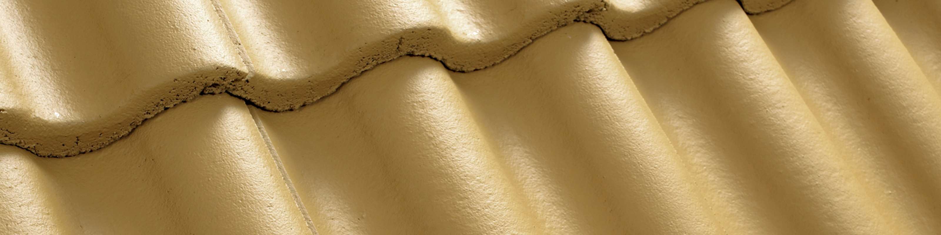 Närbild av ett gult tak med takpannor av betong.