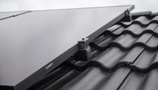Solpanel med infästning Solar på en svart takpanna. 