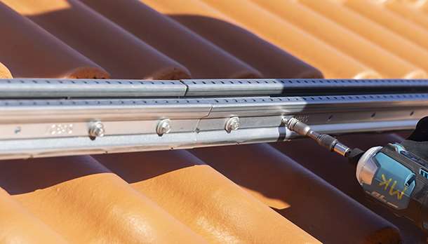 Montering av infästningsystemet Solar på ett tegelrött tak med betongtakpannor.