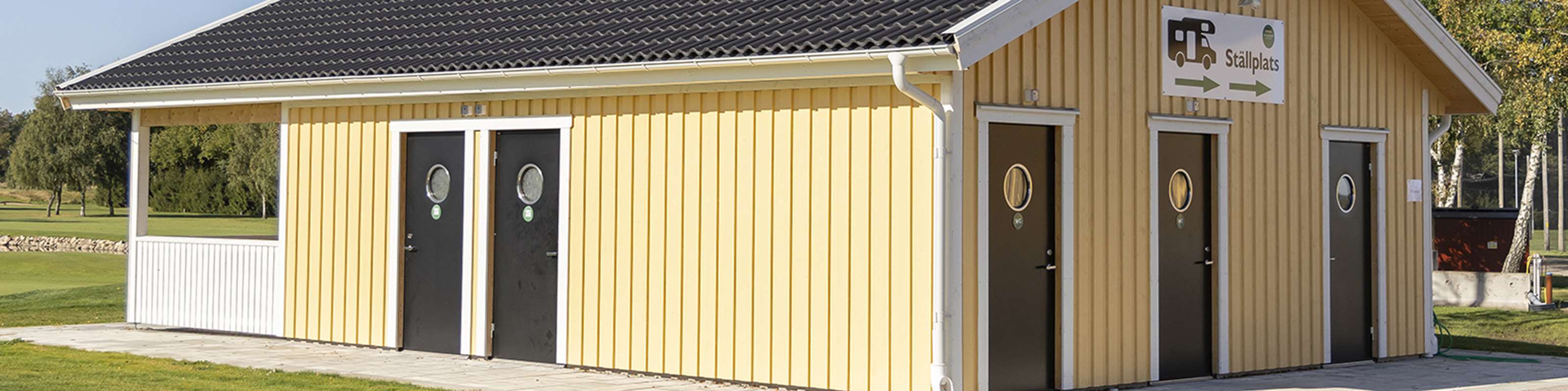 Svarta säkerhetsdörrar med rund glasöppning på ett gult hus.