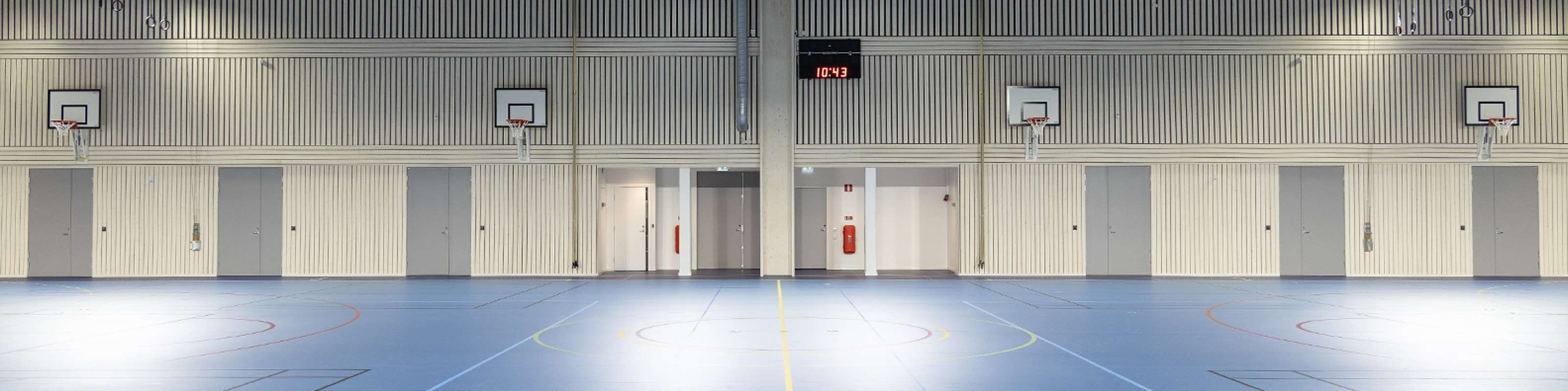 Gråa pardörrar som är branddörrar i en idrottshall.