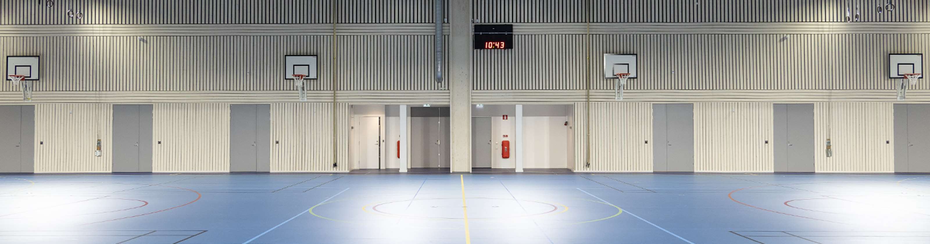 Gråa pardörrar som är branddörrar i en idrottshall.