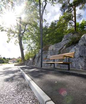 En soffa under ett träd på en trottoar. Mellan trottoar och väg finns Spikma Kantstöd.
